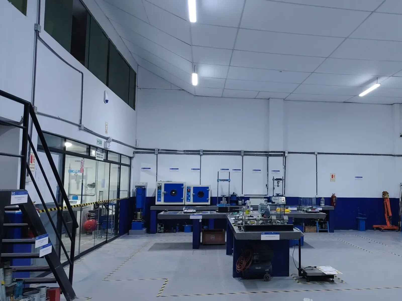 Área de ensayos del laboratorio con prensas y equipos de compresión.